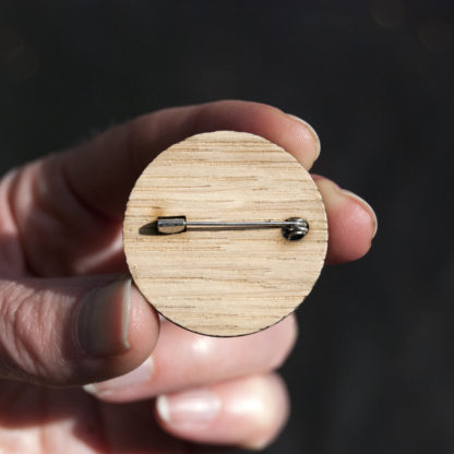 Image of the back of a wooden pin badge showing the pin fastener