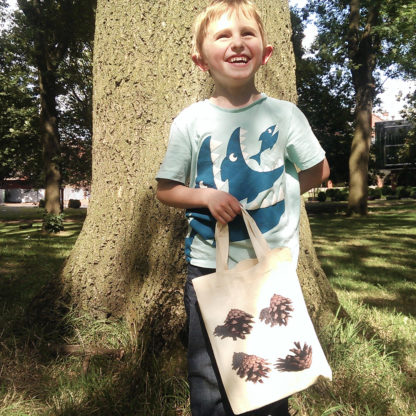 Image of a boy holding a mini tote featuring a pine cones photographic print