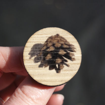 Image of pin badge featuring pine cone photo design