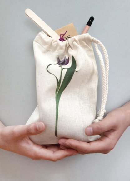 A filled cotton drawstring bag featuring a photo design of a tulip held in hands