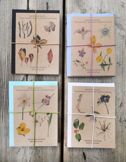 Photo of the back of four sets of seasonal note cards featuring botanical photo designs