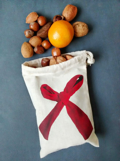 Drawstring bag with red ribbon bow design spilling nuts and fruit